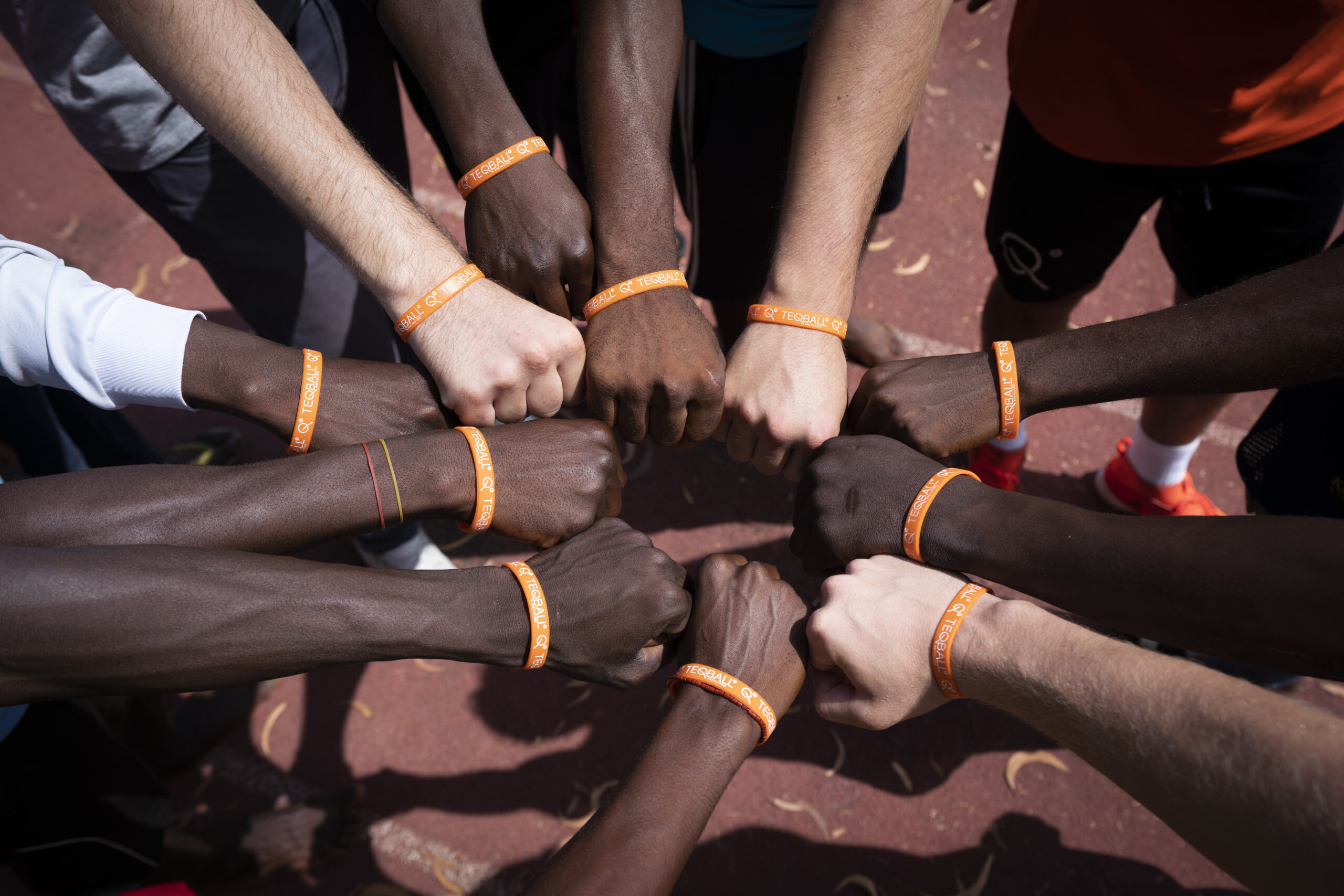 Group of diverse people fist-bumping to symbolize equality, peace, and friendship in Nigeria sports diplomatic project.